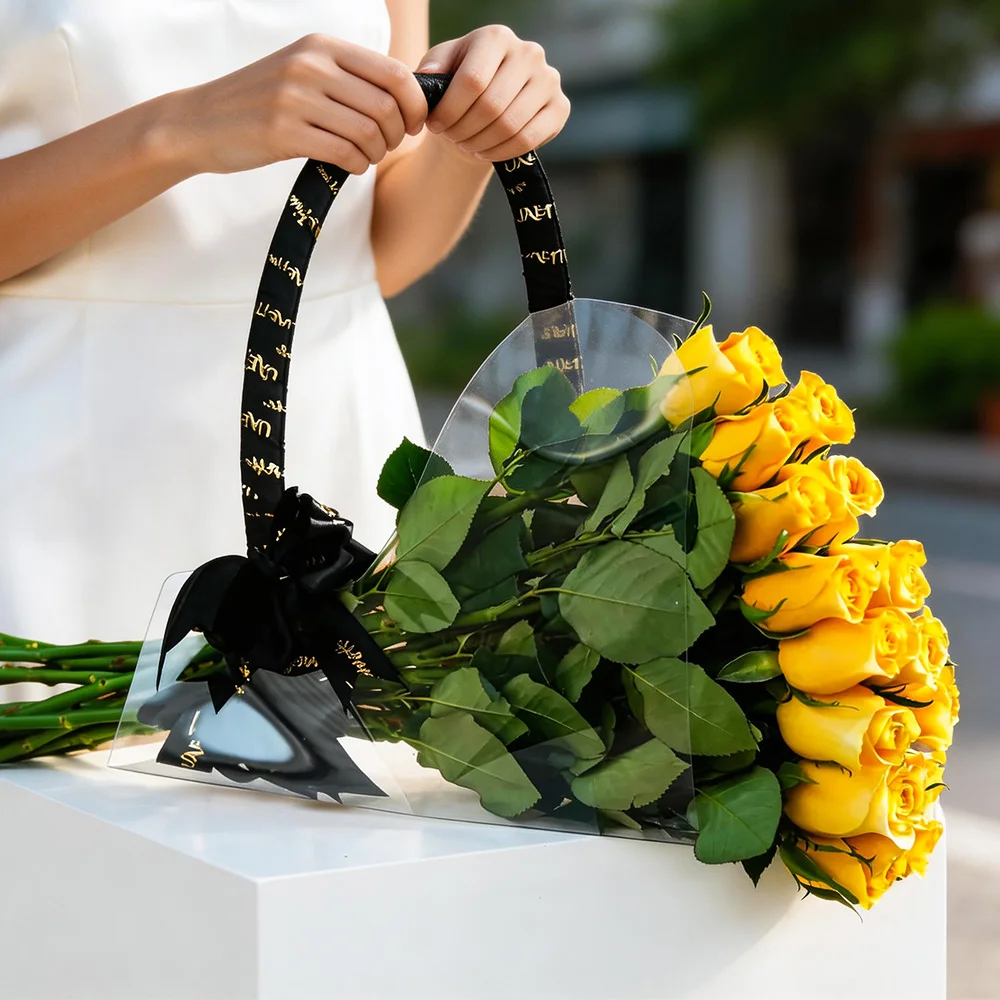 15 fresh yellow roses in an acrylic carry bag with a black ribbon