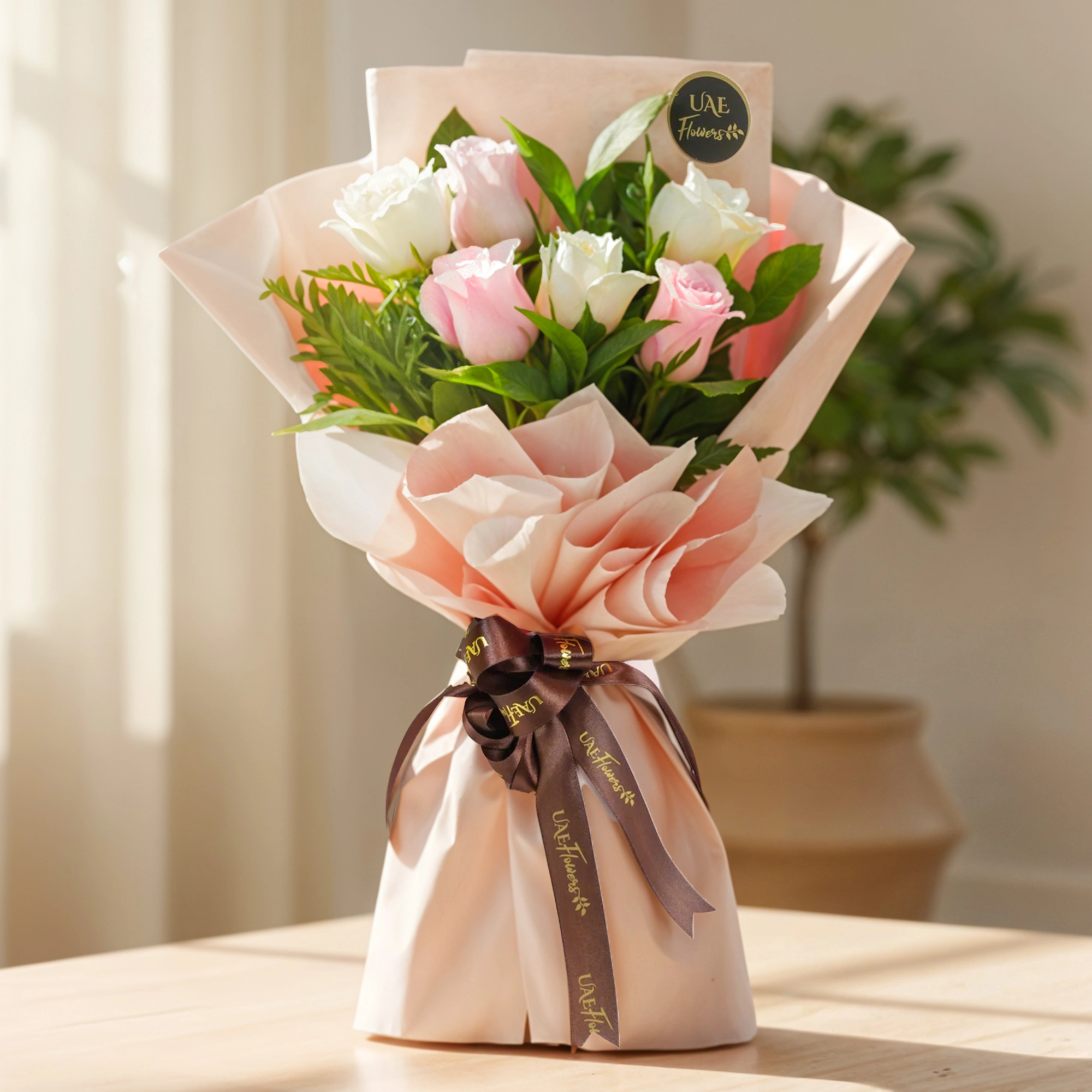 Bouquet of pink and white roses with green fillers in soft pink wrapping tied with a ribbon