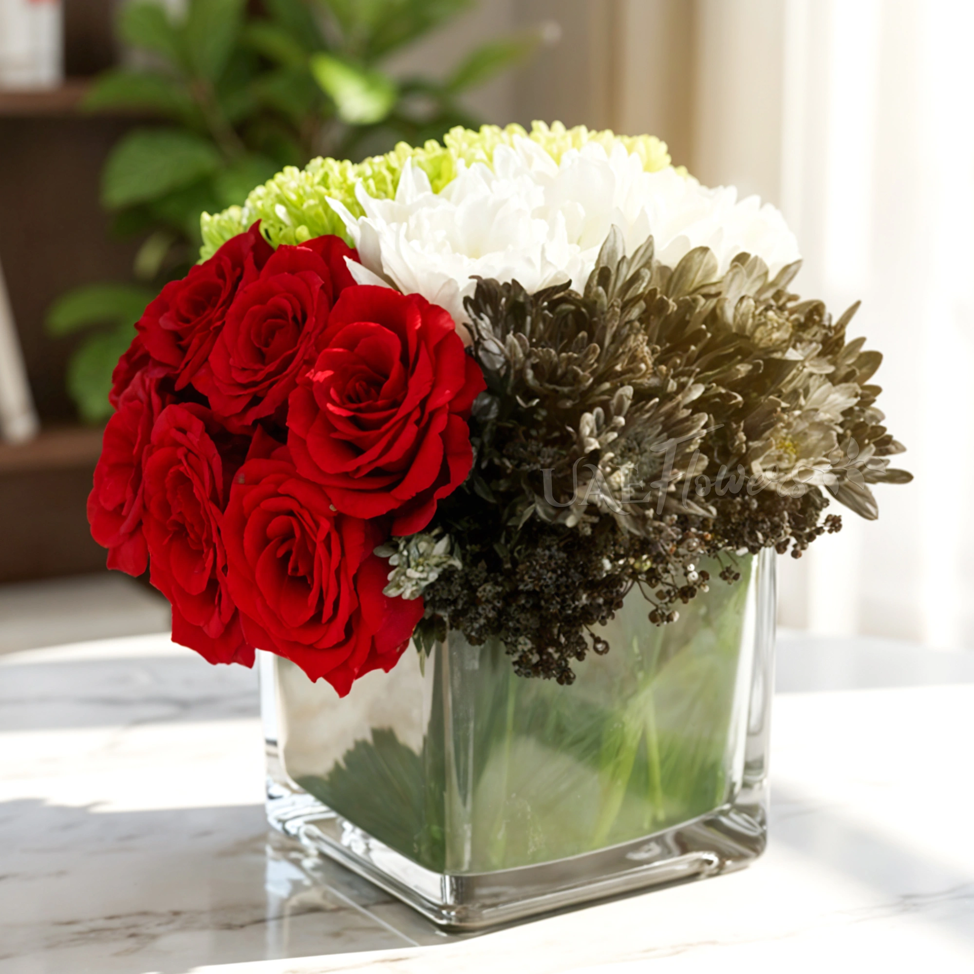 8 red roses and 12 green, white, and black sprayed chrysanthemums are arranged in a cube glass vase