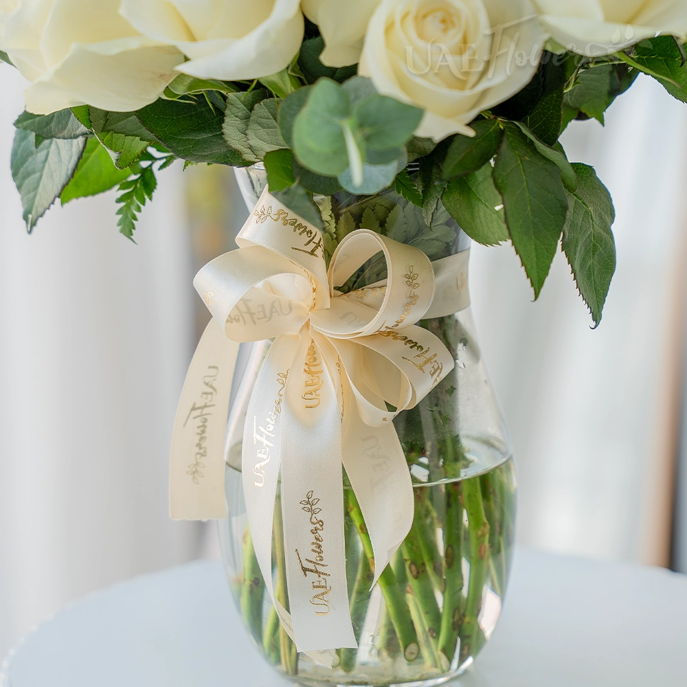 Elegant white roses in a glass vase with ribbon