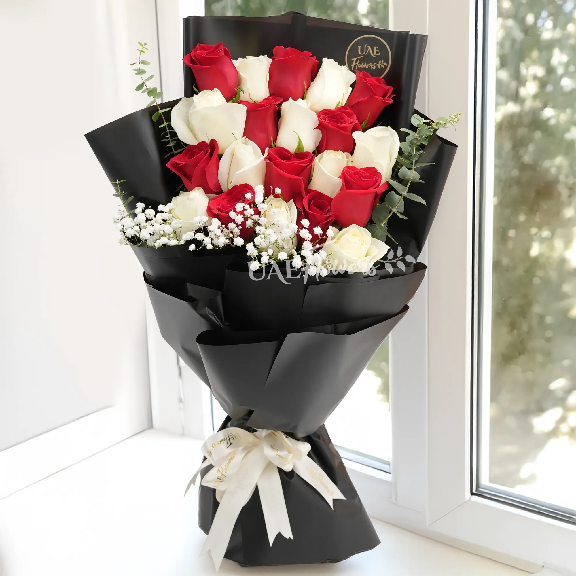 Bouquet of 10 red roses and 10 white roses with baby’s breath, wrapped in black paper and tied with a white satin ribbon.