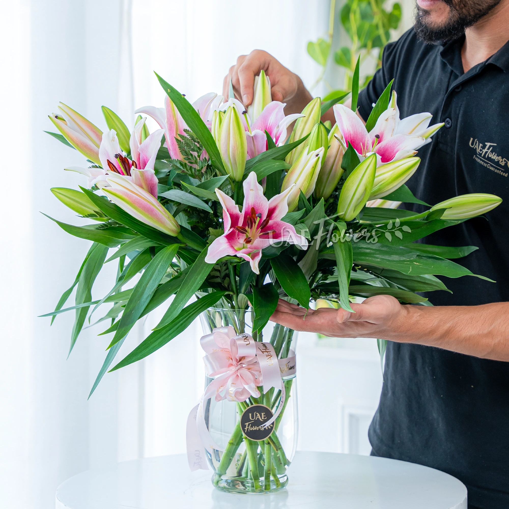 5 pink lilies with fillers in a glass vase