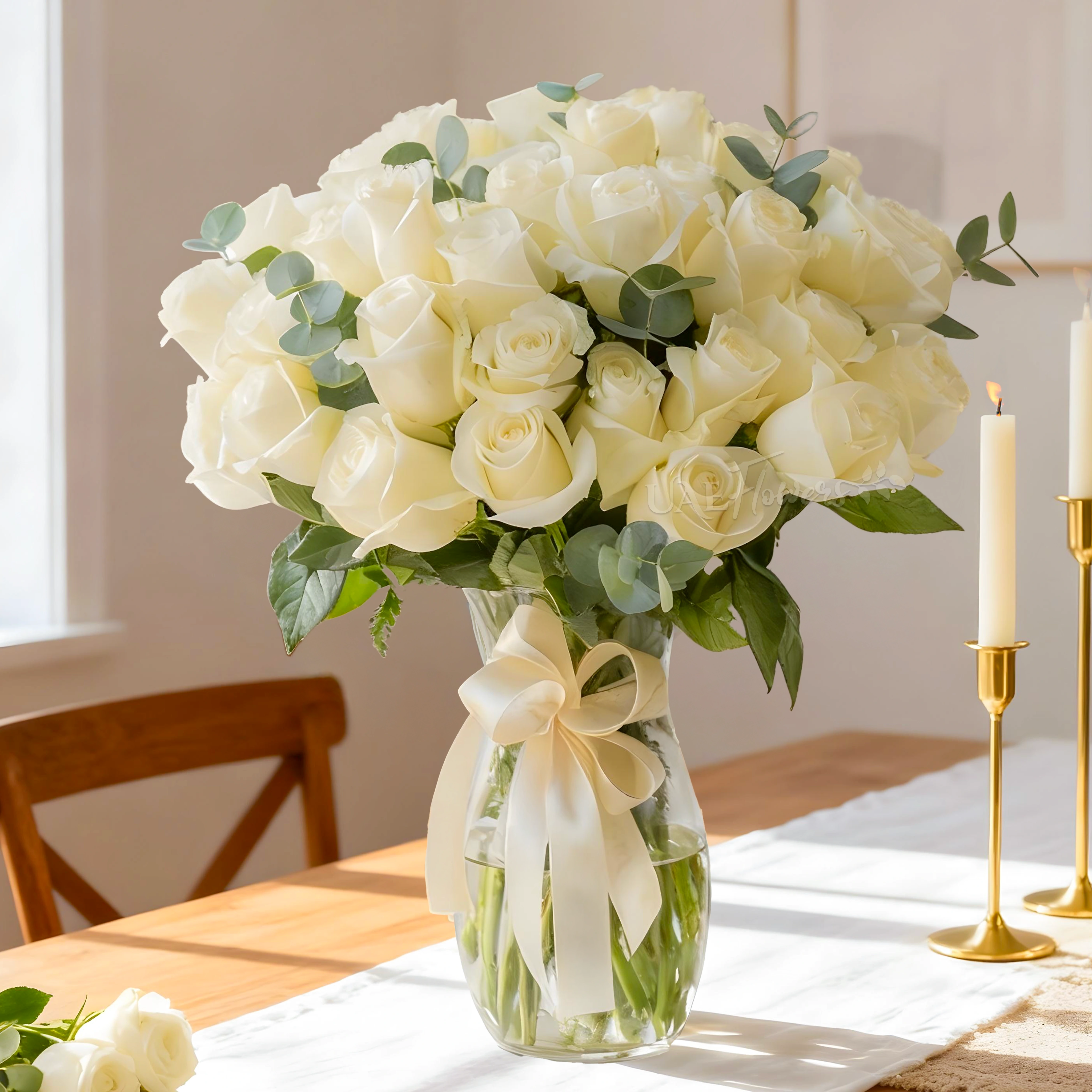 Elegant white roses in a glass vase with ribbon