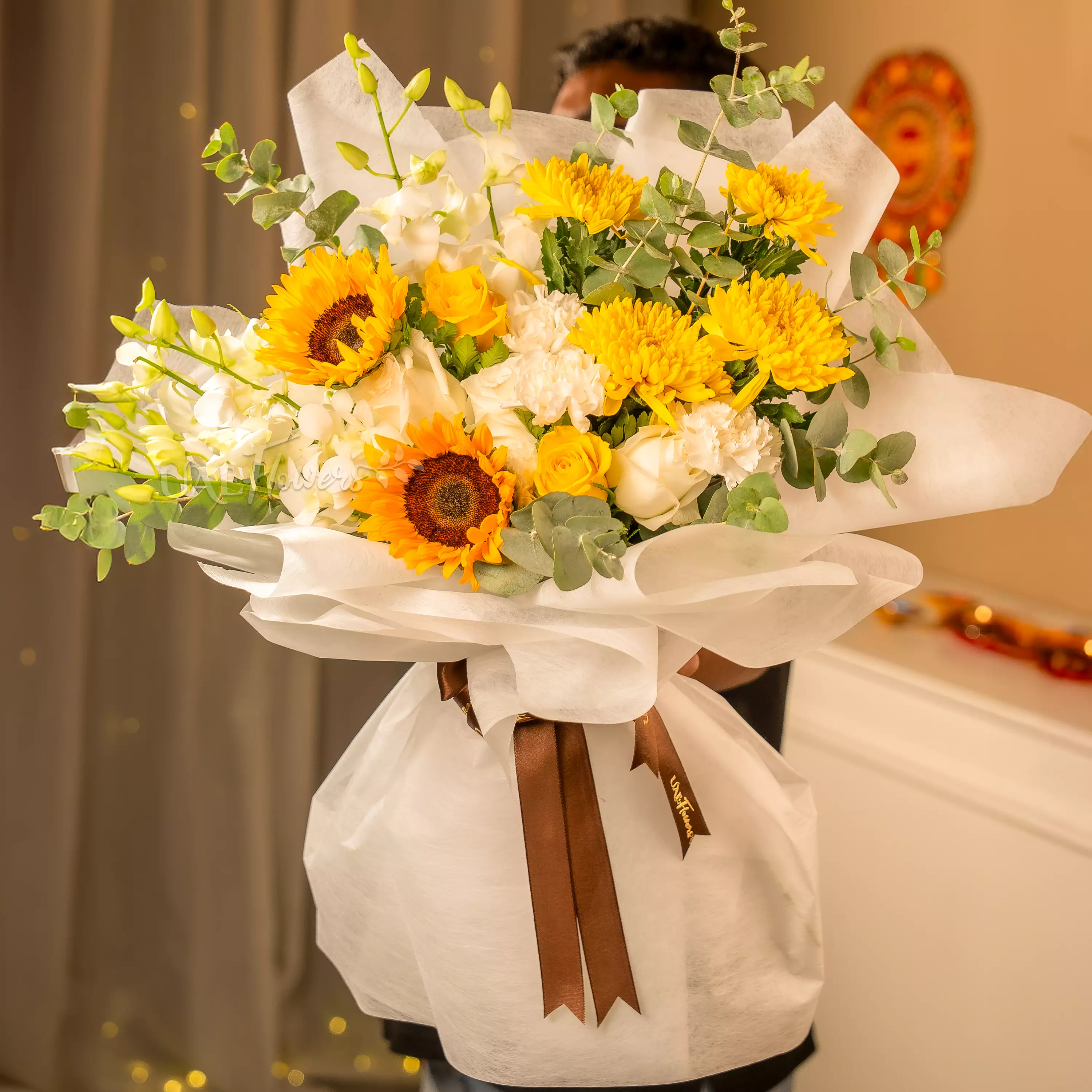 Man holding sunflower and orchid bouquet wrapped for Diwali by UAE Flowers Dubai