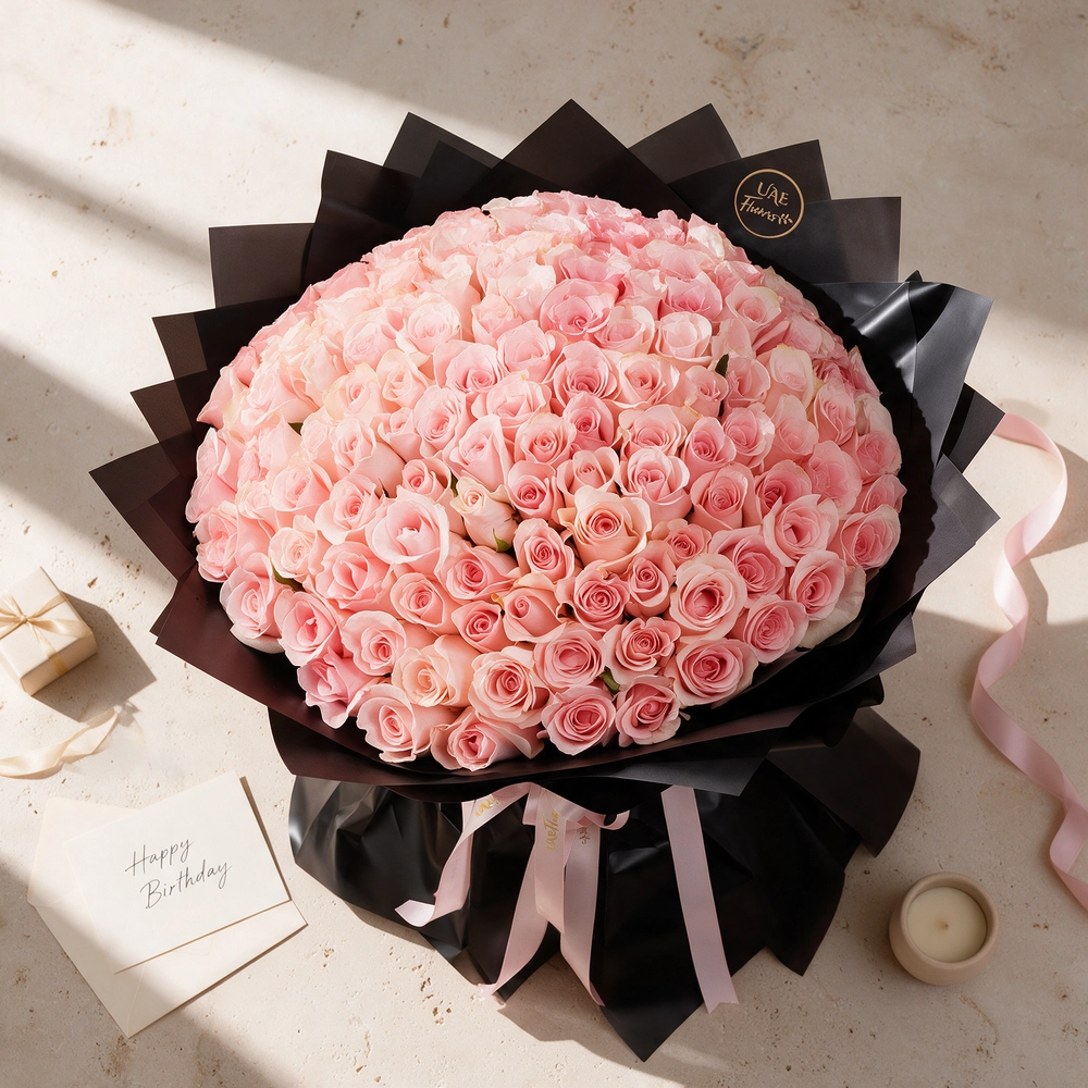 A 100-pink rose bouquet wrapped in black paper and tied with a white ribbon
