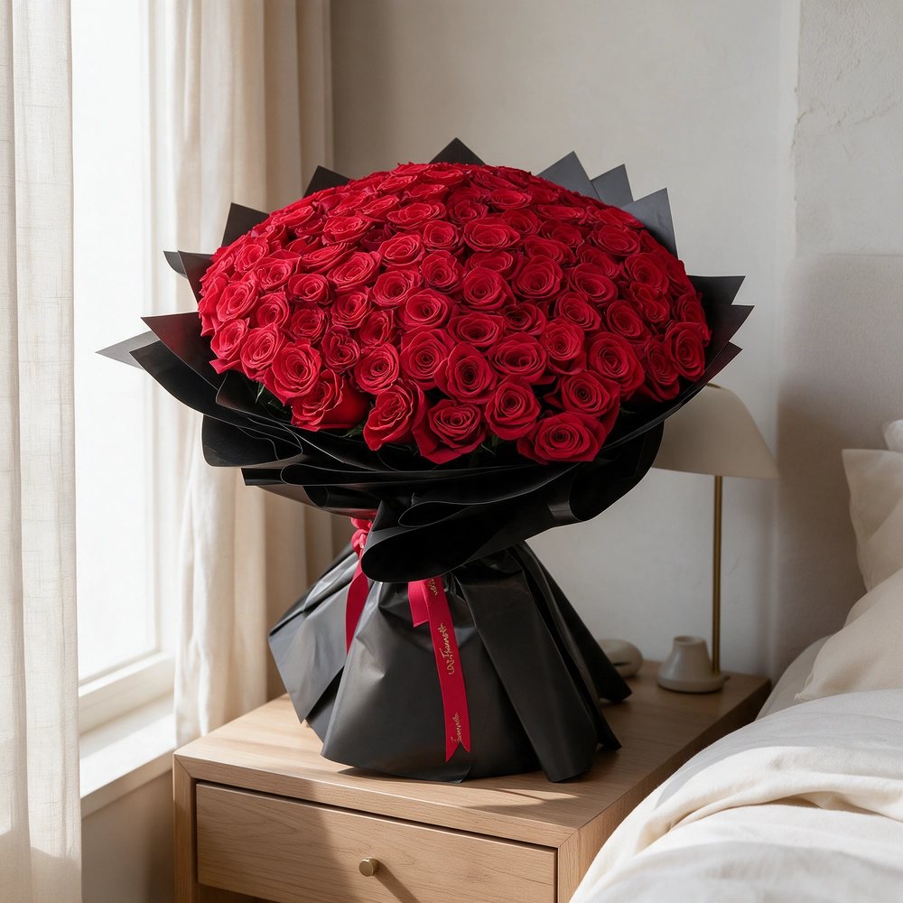 A romantic bouquet of 100 red roses in black wrapping paper tied with black ribbon