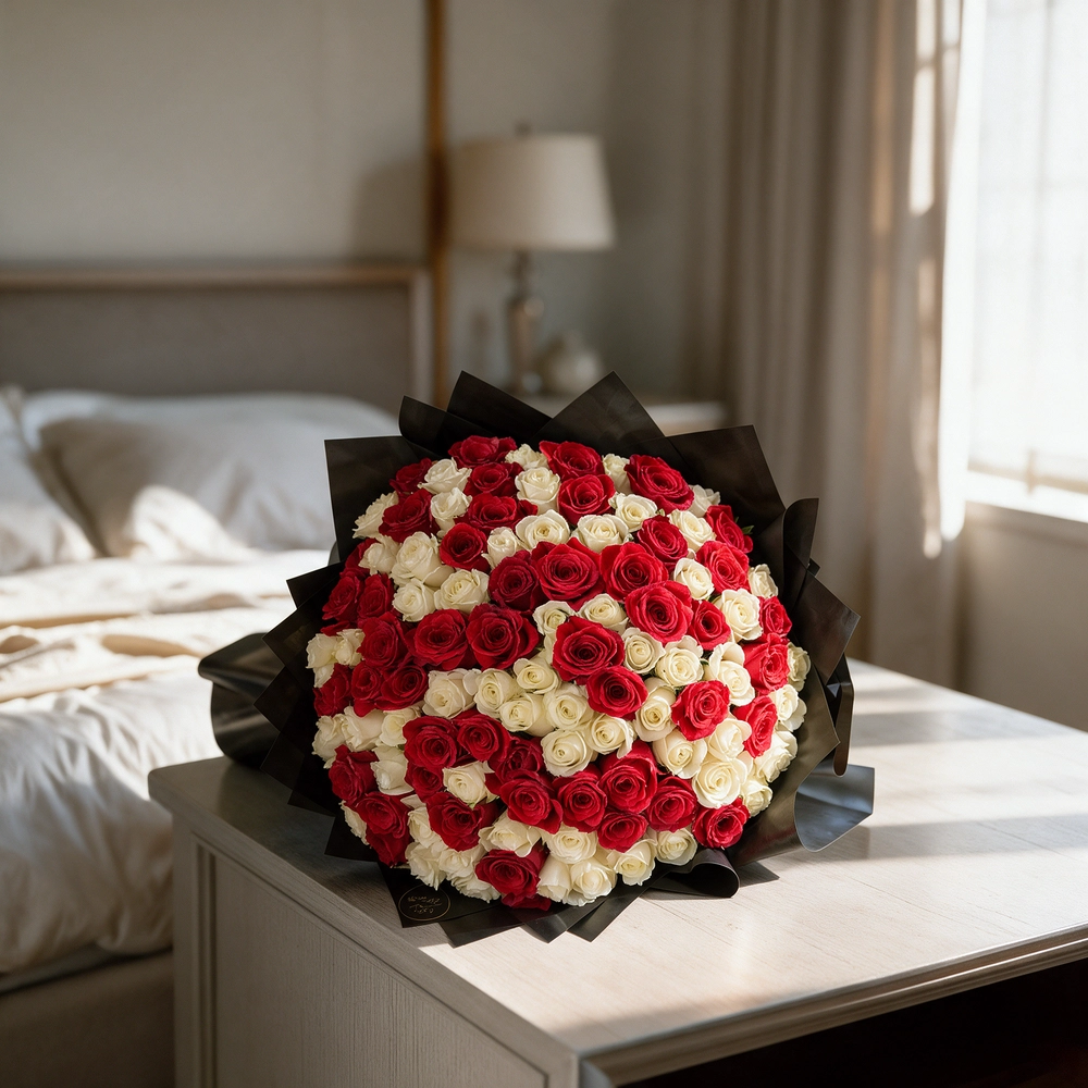bouquet of 100 red and white roses wrapped in black paper and tied with ribbons.