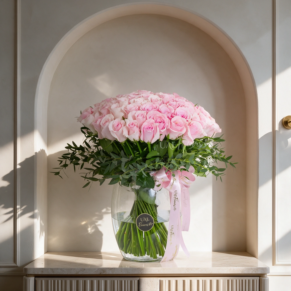 Glass vase arrangement with 40 pink roses and green fillers, tied with pink ribbons, perfect for birthdays, anniversaries, or expressing love and admiration.