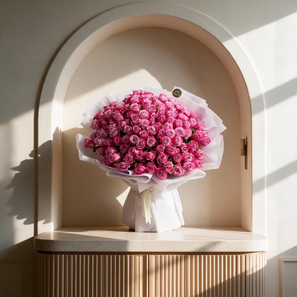 100 purple roses with fillers, wrapped in white paper and tied with ribbons