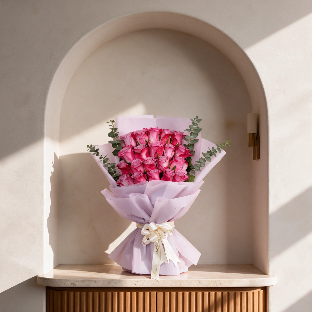 Bouquet of 20 purple roses with eucalyptus leaves, wrapped in pink paper and tied with a white satin ribbon, perfect for gifting and celebrations.