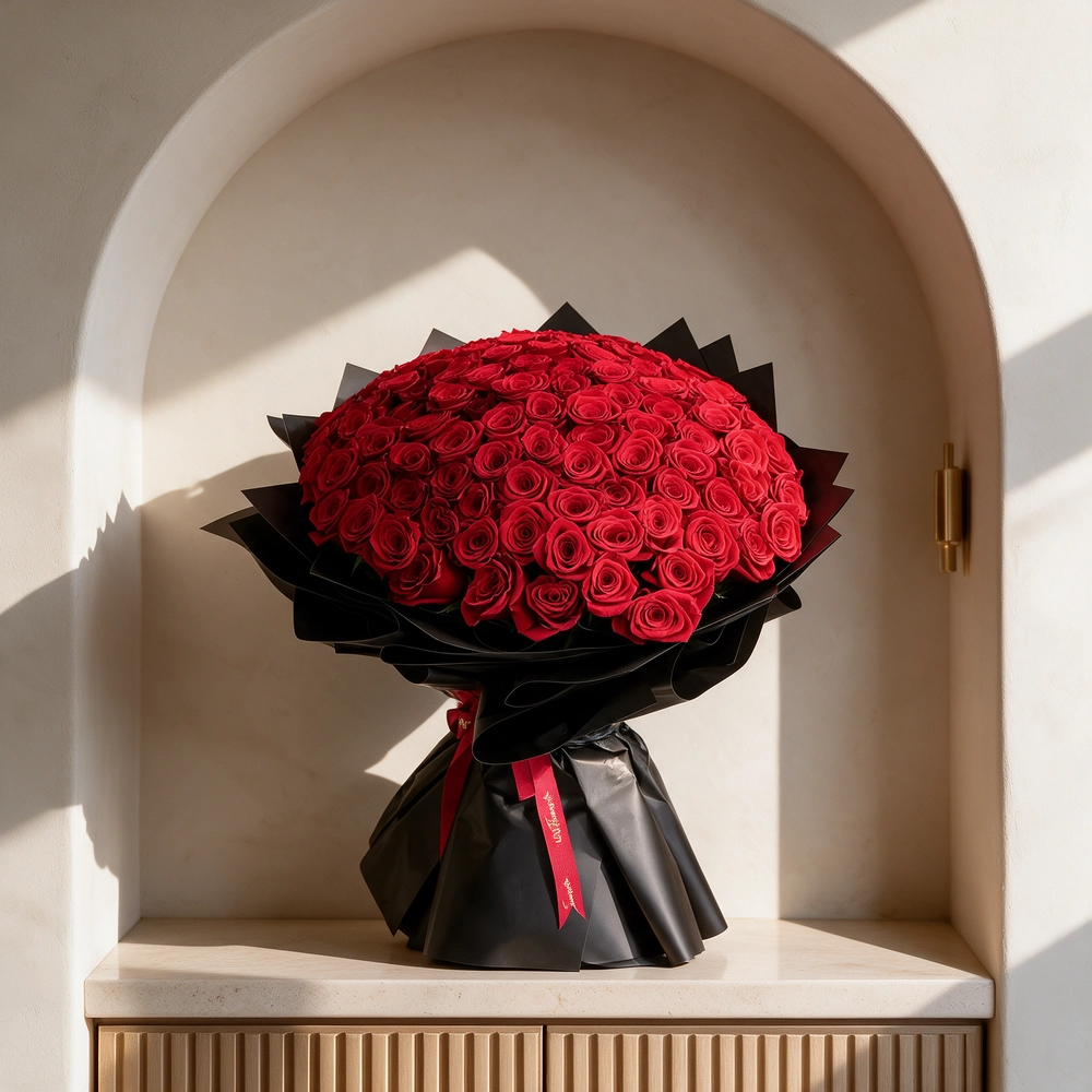 A romantic bouquet of 100 red roses in black wrapping paper tied with black ribbon