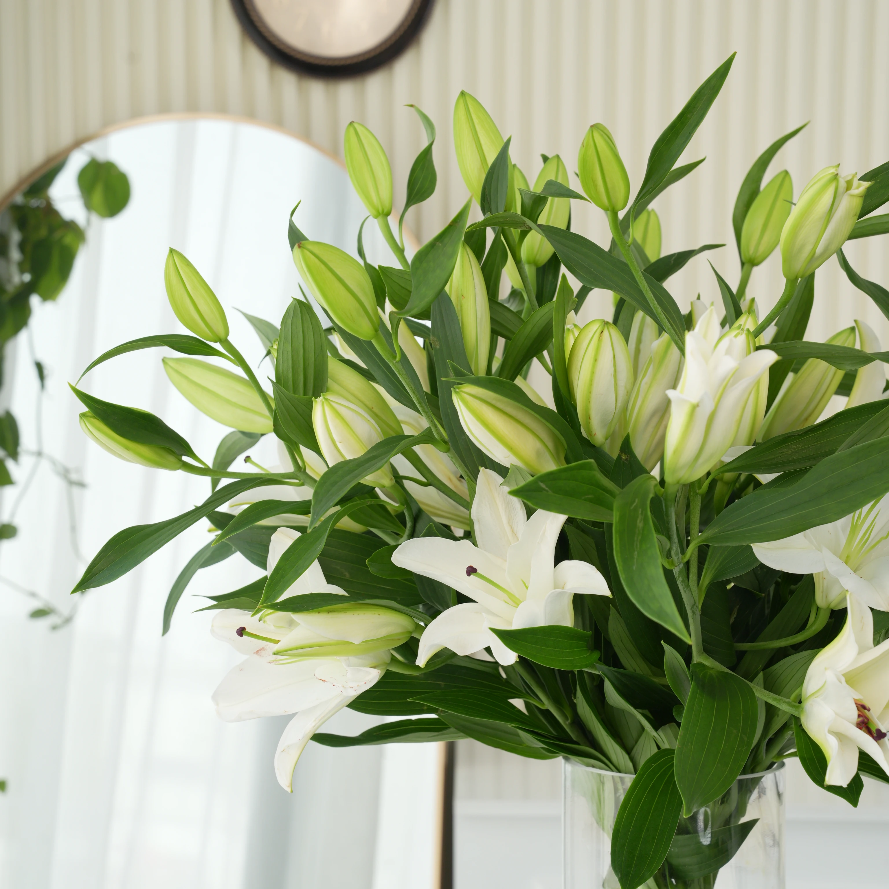 15 white lilies with green fillers in a glass vase