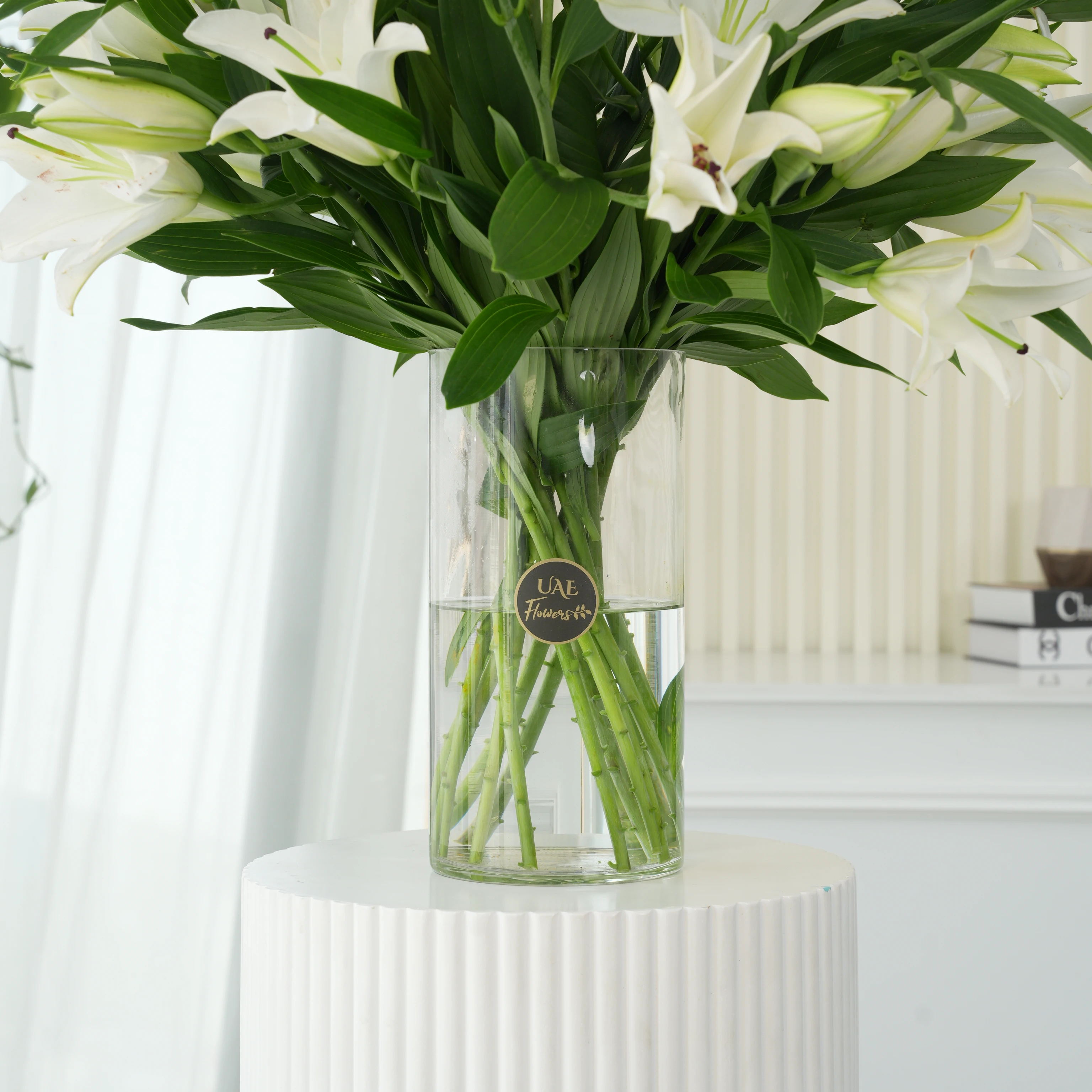 15 white lilies with green fillers in a glass vase
