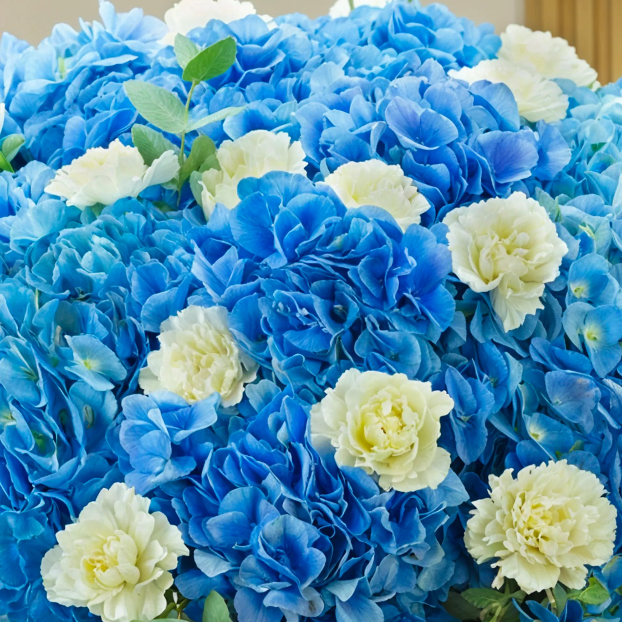 15 blue hydrangeas, 20 white carnations, and fillers, wrapped in paper with ribbon