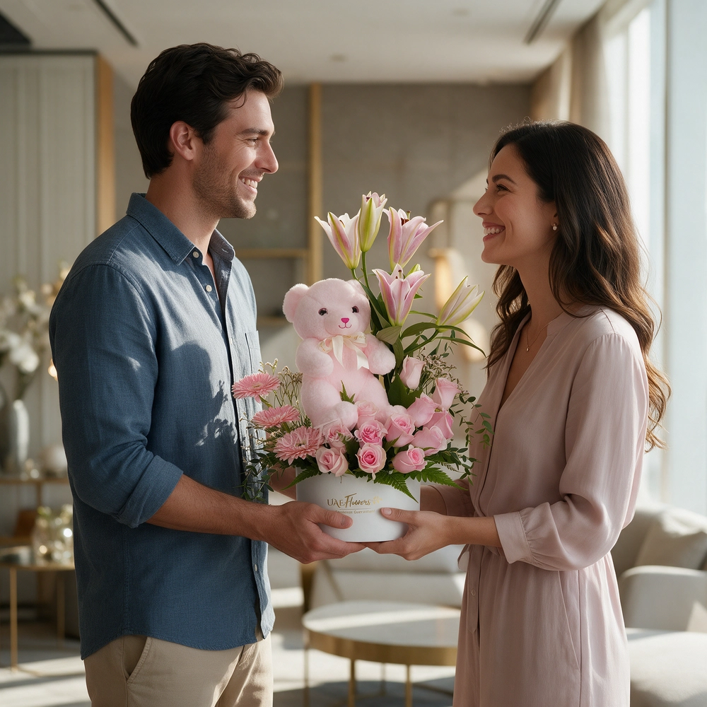 pink lily, pink gerberas, and pink roses in a round white box with a small pink teddy bear