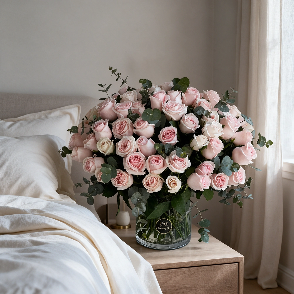 50 pink roses with eucalyptus leaves in a glass vase