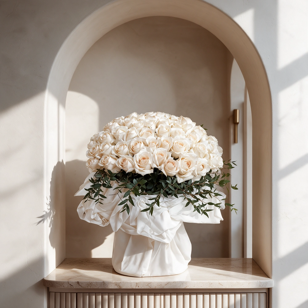A bouquet of 40 white roses with greens in white and black wrapping paper tied with a white ribbon