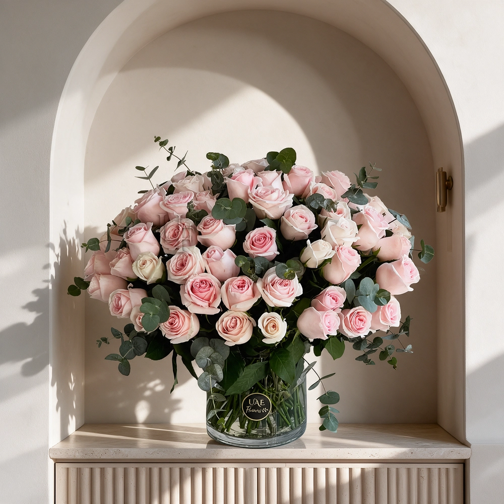 50 pink roses with eucalyptus leaves in a glass vase