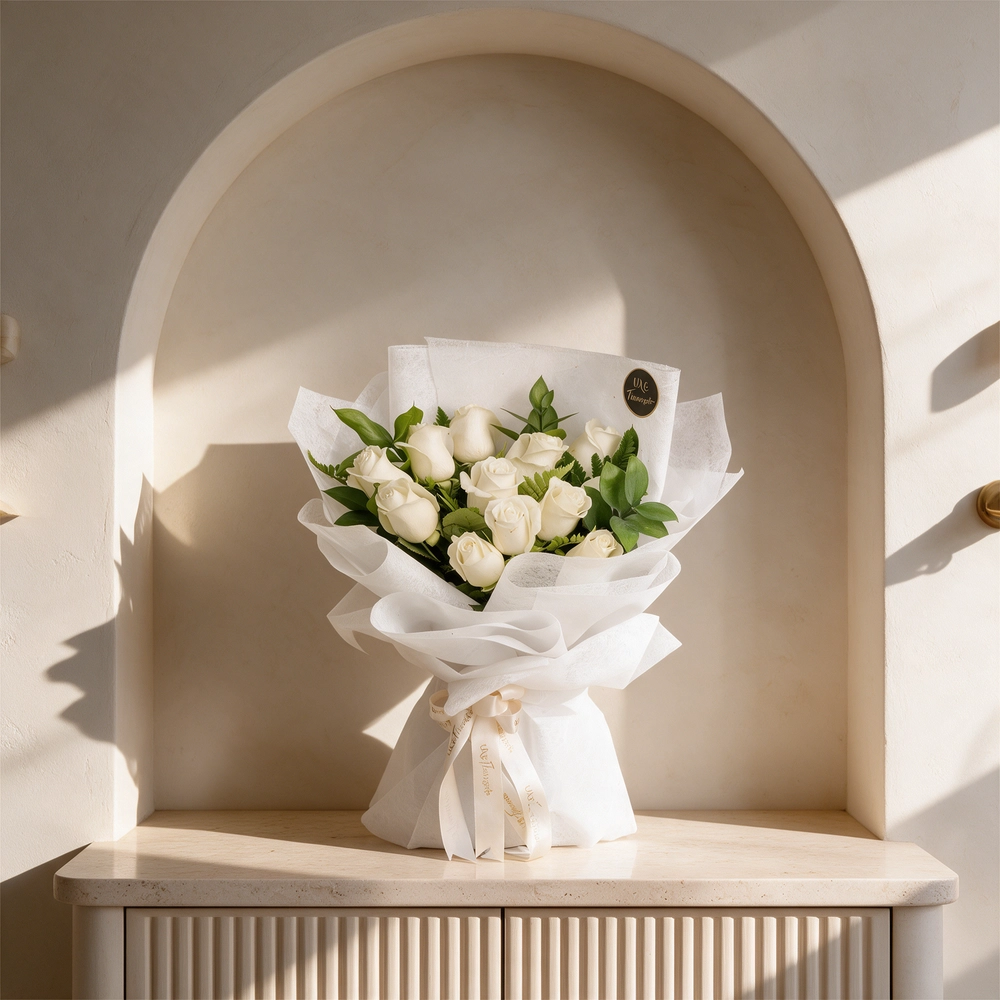 Bouquet of 12 white roses with green fillers in white wrapping paper.