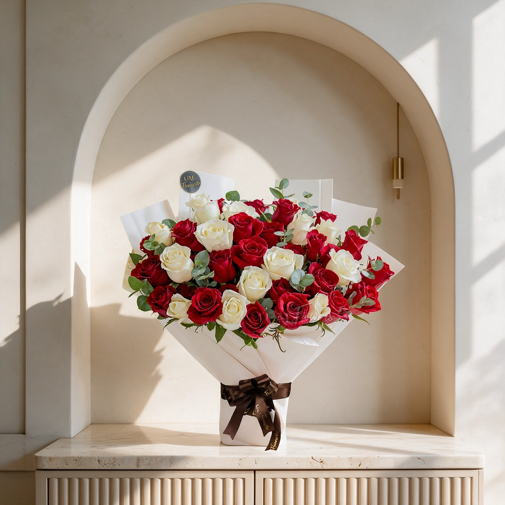bouquet of 25 red and 15 white roses with green fillers in paper packing tied with ribbons