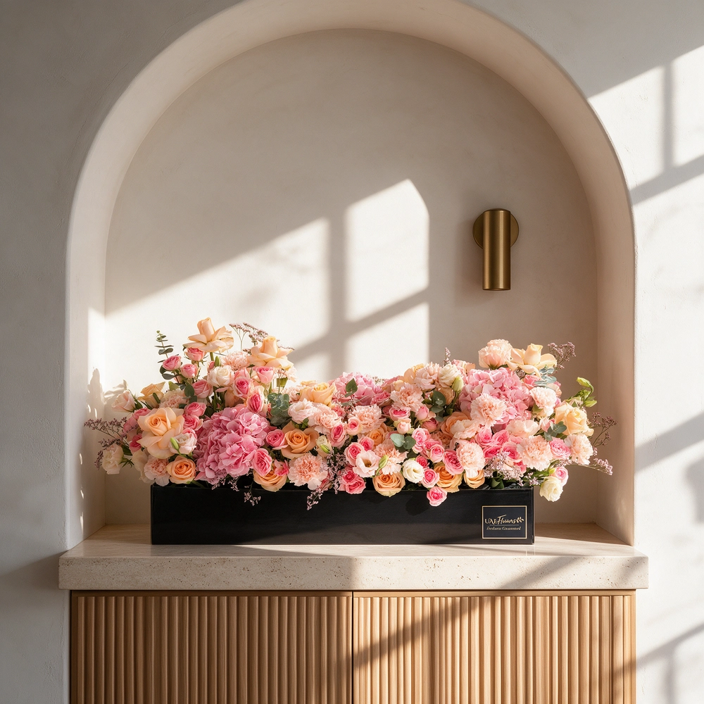 Arrangement of 20 peach roses, 20 pink carnations, 20 pink spray roses and 3 pink hydrangeas with green fillers in a long black box.