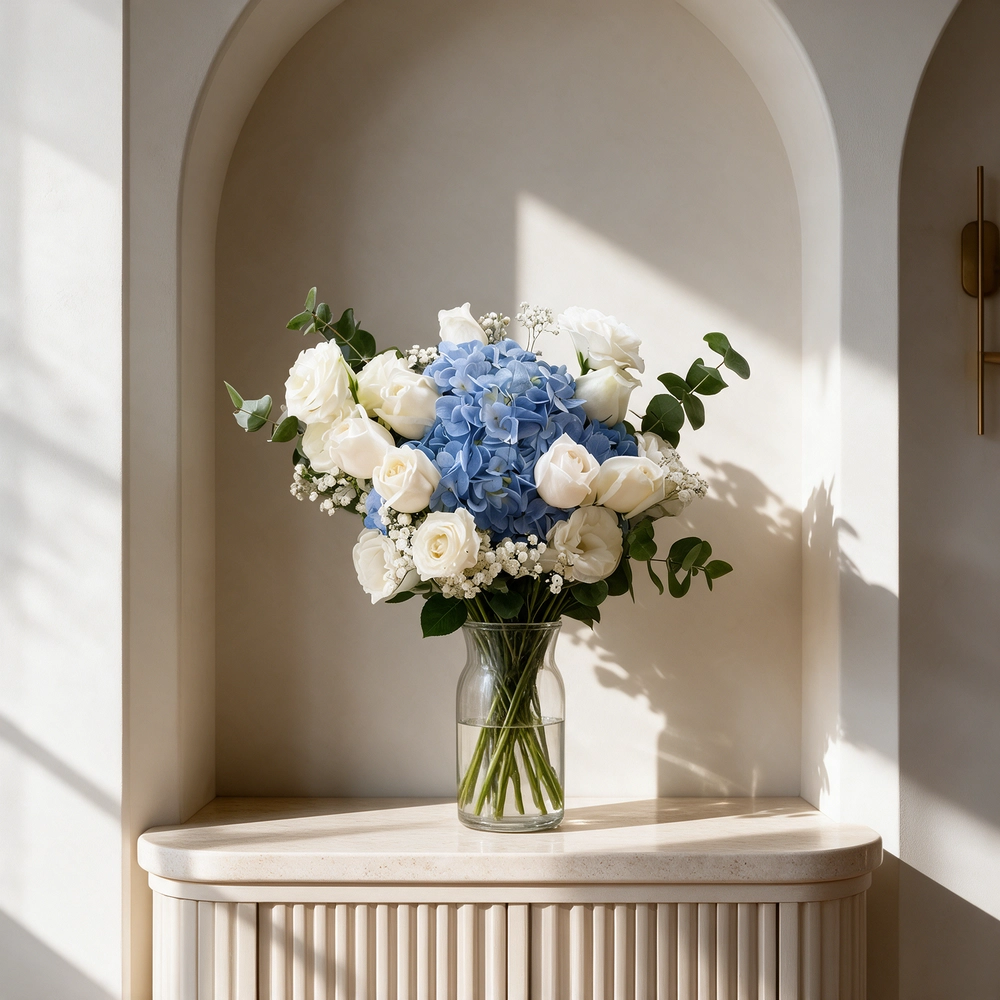 A bouquet of 1 blue hydrangea and 14 white rose with baby breath in blue and white wrapping paper tied with white ribbon